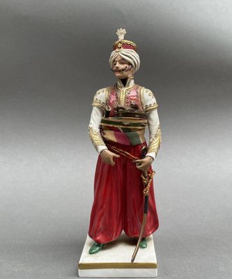 une figurine représentant un homme coiffé d'un turban et tenant une canne