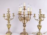 trois chandeliers anciens en laiton, chacun orné de bougies
