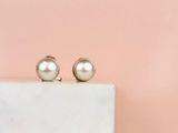 a pair of pearl earrings sitting on top of a marble block