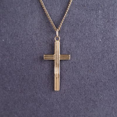 un gros plan sur une croix suspendue à un collier, portée par un mannequin, un mannequin, un mannequin, un mannequin, un mannequin, un mannequin, un mannequin