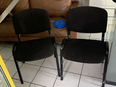 deux chaises noires placées l'une à côté de l'autre sur un sol carrelé