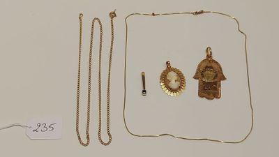 deux colliers en or et une paire de boucles d'oreilles posés sur une surface blanche