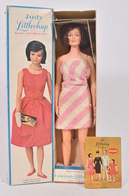 une poupée dans une boîte sur laquelle figure l'image d'une femme en robe rose