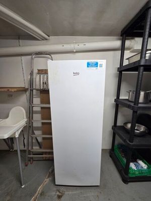 a white refrigerator in a room with shelves and a chair