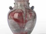 a red vase sitting on a white surface with a white background