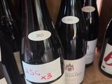 plusieurs bouteilles de vin rouge sont alignées sur une étagère