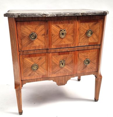 a small wooden chest of drawers with marble top