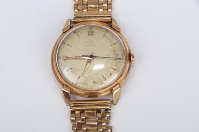une montre en or montée sur un bracelet en or, posée sur une surface blanche