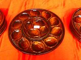 trois assiettes marron posées sur une nappe orange, sur une table