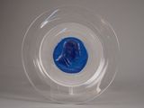 une pièce bleue dans un bol transparent posé sur une surface blanche