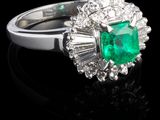 une bague en émeraude et diamant sur une surface noire