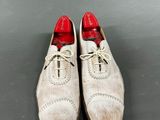 a pair of white shoes with red soles on a gray surface