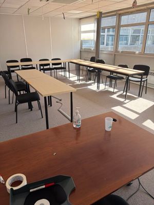 des tables et des chaises dans une pièce vide, avec un ordinateur portable posé sur la table