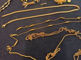 several gold necklaces and bracelets on a black surface