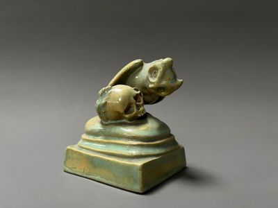un gros plan sur une statue représentant un oiseau surmonté d'un crâne