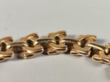 a close up of a gold chain bracelet on a white surface