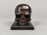 bronze skull on black marble base on white background