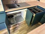 a kitchen with a sink and a trash can in it