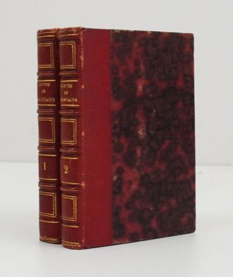 un vieux livre posé sur une table blanche à côté d'un livre rouge
