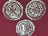 trois dessous de verre en verre posés sur un tissu rouge, sur fond rouge