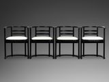 quatre chaises noires avec des coussins blancs sur fond gris