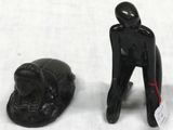 figurine of a man with a hat next to a black object on a white surface