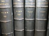 several old books are lined up in a row on a shelf