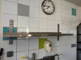 a clock that is on the wall above the kitchen sink