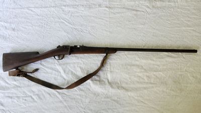 le fusil est posé sur un lit recouvert d'un drap blanc