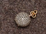 un gros plan sur un pendentif Locke en or et diamants, muni d'une chaîne