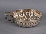 une assiette ancienne en argent avec une anse, sur fond gris