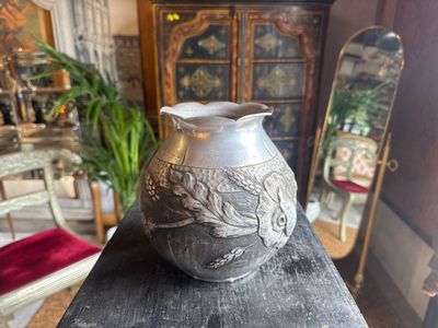 a silver vase sitting on top of a wooden table