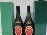 two bottles of liquor sitting next to a green box on a white surface