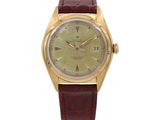 a gold watch with a green dial and brown leather strap