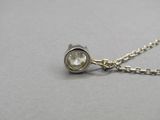 un gros plan d'un collier en argent orné d'un diamant blanc