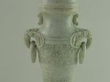 un vase blanc surmonté d'une statue