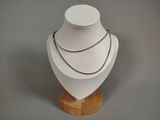 a white mannequin on a wooden stand with a necklace on it
