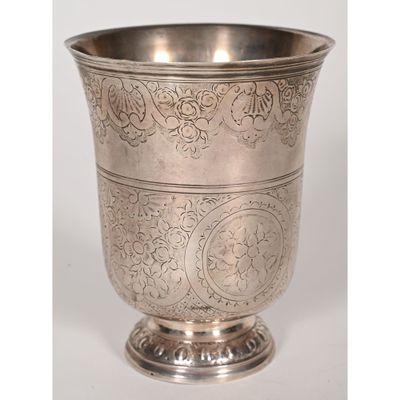 an antique silver cup with a floral design on the rim