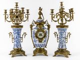 three blue and white vases with a clock on them