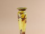 yellow and brown vase with birds on it sitting on a white surface