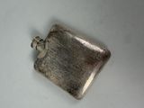 a small silver flask on a white surface
