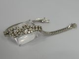 a silver bracelet with crystal beads and a chain on a white surface