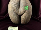une sculpture en bois représentant une fesse, sur laquelle est collé un autocollant