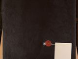a black canvas with a red button on it sitting on top of a wooden easel