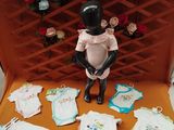 a doll that is sitting in a chair with baby clothes on it