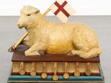 a statue of a sheep with a flag on top of a book