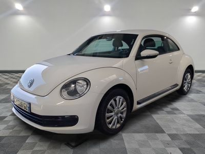 une photo d'une Coccinelle Volkswagen blanche garée sur un sol à damier