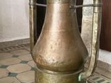 a large brass vase sitting on the floor in front of a door