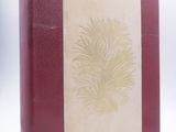 an old book with a red cover sitting on top of a white table