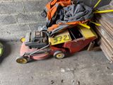 a lawn mower that is sitting next to a pile of wood